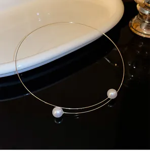 Vue détaillée d'un tour de cou minimaliste en fil doré avec deux perles blanches élégantes