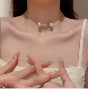 Vue détaillée d'un collier choker minimaliste en fil d'acier avec deux perles blanches.