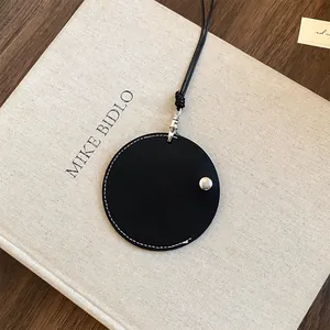 Vue détaillée d'un porte-lunettes rond en cuir noir avec des surpiqûres blanches