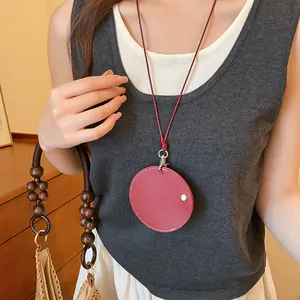Détail d'un collier pendentif rond en cuir bordeaux utilisé comme porte-lunettes sur modèle