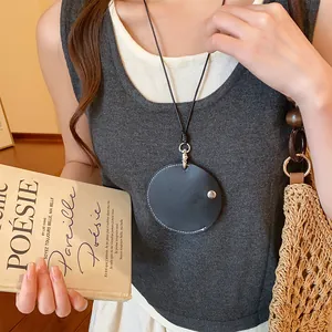 Gros plan d'un collier porte-lunettes rond en cuir noir porté comme un pendentif élégant.
