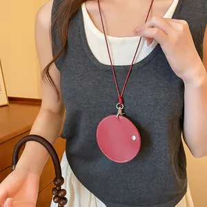 Détail d'un collier porte-lunettes avec pendentif rond en cuir rouge sur modèle