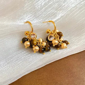 Close-up of vintage gold earrings featuring brown beads and zircon on textured cloth