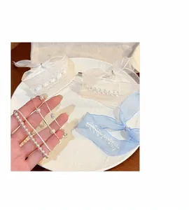 Vista dettagliata di eleganti braccialetti di perle in mano con fiocchi in organza decorativi
