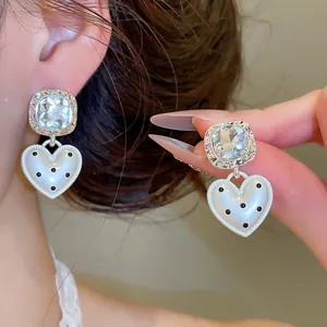 Détail rapproché de boucles d'oreilles cœur à pois avec des clous en diamant
