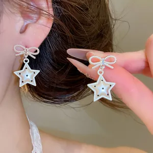 Gros plan sur d'élégantes boucles d'oreilles nœud en argent avec pendentifs étoiles à pois