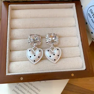 Vue détaillée de boucles d'oreilles cœur en argent à pois noirs dans une boîte