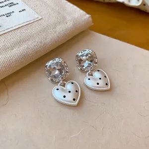 Détail rapproché de boucles d'oreilles cœur blanc avec pois noirs et cristaux brillants