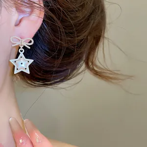 Gros plan de boucles d'oreilles nœud en argent avec pendentif étoile et motif à pois
