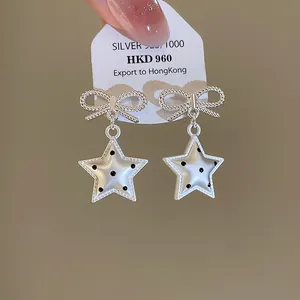 Vue détaillée de boucles d'oreilles nœud en argent avec pendentifs étoiles à pois