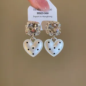 Gros plan de boucles d'oreilles en forme de cœur à pois noirs et montures argent