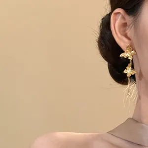 Vue rapprochée de boucles d'oreilles papillon dorées vintage avec glands et strass
