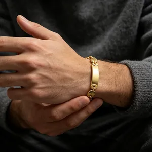 Detailopname van een goudkleurige titaniumstalen armband met varkensneusschakels en plaat.