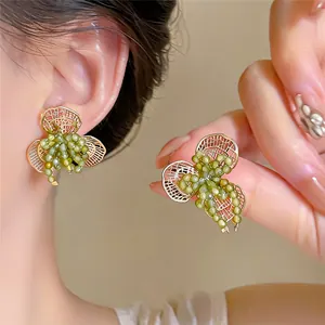 Detailopname van elegante goudkleurige bloemenoorbellen met levendige groene kralen