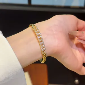 Detailed view of an 18K gold-plated bangle with pavé-set zircons on a woman's wrist