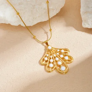 Vue détaillée du collier pendentif feuille dorée baroque avec des touches d'émail blanc.