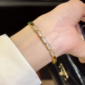 Close-up detail of an 18K gold plated bangle with sparkling zircons worn on a wrist.