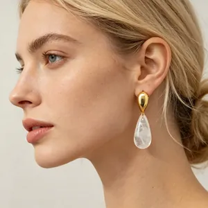 Detailansicht eleganter goldener Tropfenohrringe mit Marmorharz-Detail an einem Modell