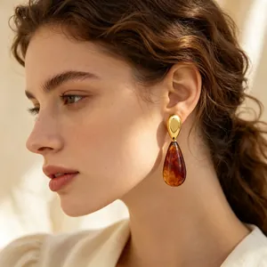 Detailaufnahme eines eleganten bernsteinfarbenen Tropfenohrrings am Ohr eines Modells