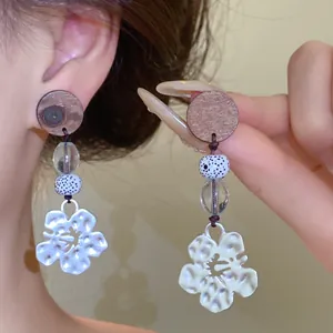 Detailweergave van houten en glazen kralen oorbellen met zilveren bloemhanger