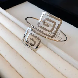 Close-up of a silver geometric open cuff bracelet with a stylish Greek key pattern