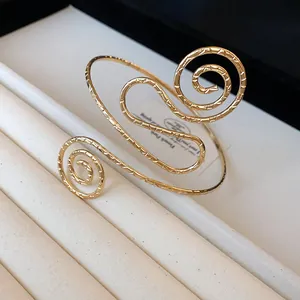 Close-up of a gold-toned textured metal arm cuff with a unique spiral design.
