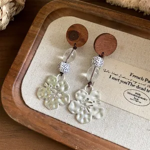 Detailopname van handgemaakte oorbellen met houten schijven, glaskralen en zilveren bloemen