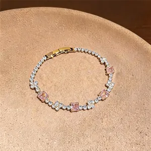 Eleganter goldener Armreif mit rosa quadratischen Zirkonia-Steinen auf Teller