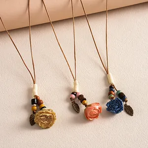 Gros plan sur trois colliers ethniques avec roses en céramique et perles en bois
