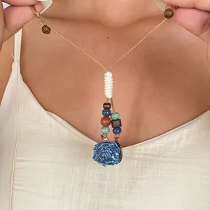 Gros plan d'un collier de style ethnique avec pendentif fleur bleue et perles en bois sur mannequin