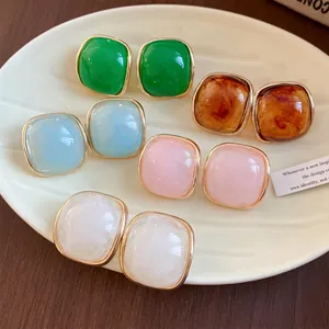 Detailed view of resin square stud earrings in various pastel colors and amber