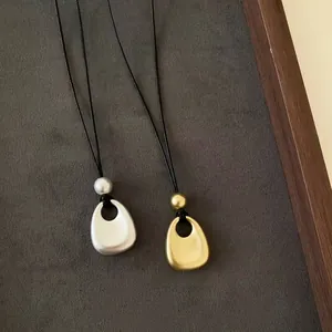 Zoom sur des pendentifs gouttes en métal mat minimaliste en finitions or et argent