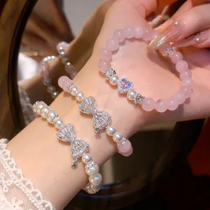 Nahaufnahme von Rosenquarz und Perlenarmbändern mit funkelnden Zirkonia Schleifenanhängern