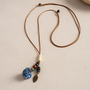 Détail d'un collier ethnique en cuir avec fleur en céramique bleue et perles de bois