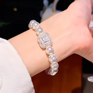 Detailansicht eines Perlenarmbandes mit rechteckigem Zirkonia-Mittelstück am Handgelenk.
