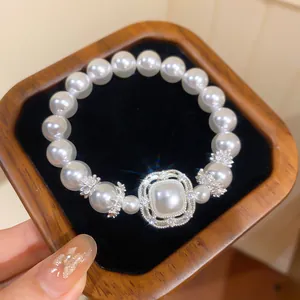 Nahaufnahme eines eleganten Perlenarmbands mit einem glitzernden Zirkon-Anhänger im Holzkästchen