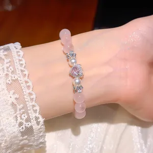 Nahaufnahme von Armband aus rosa Katzenaugenstein und Perlen mit Herz-Zirkonia-Anhänger.