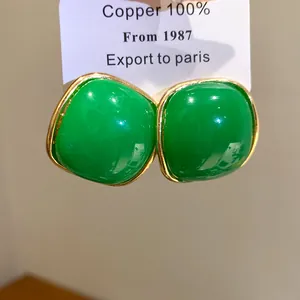 Macro detail of vintage-style green resin stud earrings with gold-plated copper borders