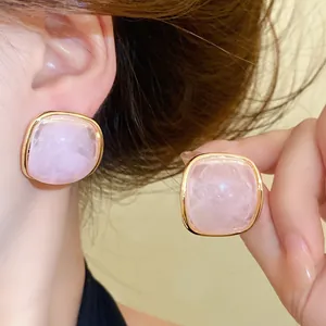 Detail view of pink marbled resin stud earrings with a gold-toned square bezel
