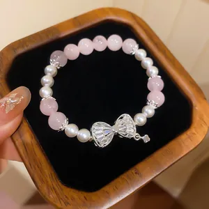 Detailansicht eines eleganten Armbands mit rosa Katzenauge, Perlen und Zirkonia-Schleife