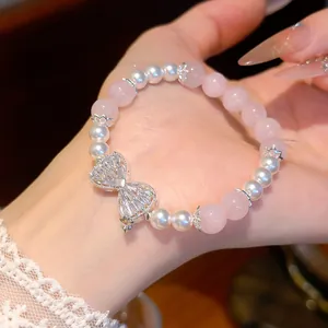 Detailansicht eines Armbands aus rosa Rosenquarz und Perlen mit Zirkonia-Schleife.