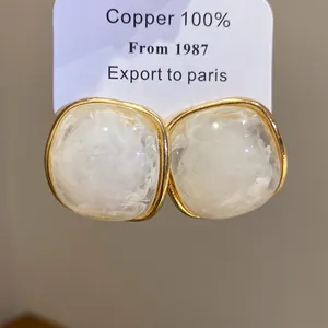 Close-up detail of square resin earrings with gold-toned frame and marble effect