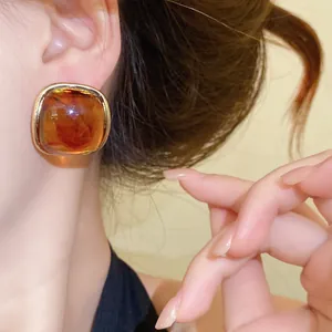 Detailed macro view of vintage amber resin square stud earrings on ear