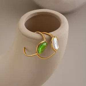 Close-up of French vintage gold-plated rings with green and white gems on a vase