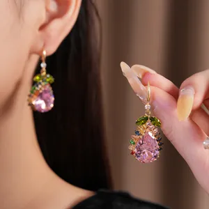 Gros plan de boucles d'oreilles vintage en forme de goutte avec zircon rose et gemmes.