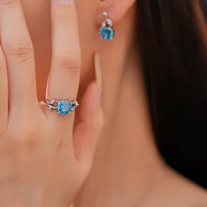Close-up of elegant silver floral ring with blue zircon gemstone on model's hand
