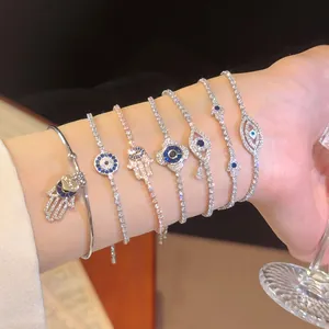Detailansicht von mehreren glitzernden Armbändern mit bösem Blick und Hand der Fatima