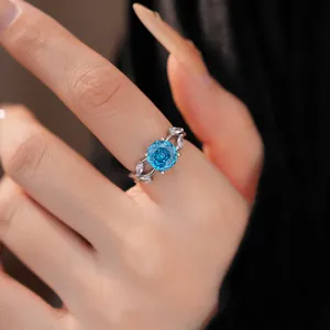 Close-up of elegant silver ring with blue rose-shaped zircon and leaf details