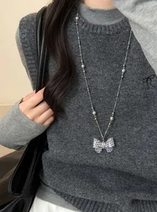 Detailopname van een lange ketting met een zwart-wit gestippelde strikhanger voor dames