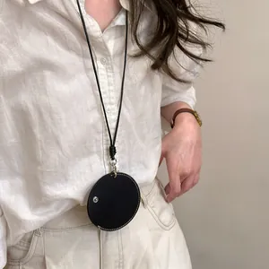 Gedetailleerde close-up van een zwarte lederen ronde brillenhouder ketting op een model